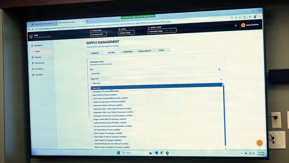 A computer monitor displays a military chapel administration web application called 'CHAP' (Chapel Administration Pattern) showing a Supply Management module. The screen is set at Fort Leavenworth's Frontier Chapel and shows a 'Log Supply Usage' form with a dropdown menu of available inventory items. The banner at the top indicates this is 'CONTROLLED UNCLASSIFIED INFORMATION'.