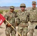 Three U.S. Army soldiers in MultiCam (OCP) camouflage uniforms pose together in a desert training environment. The soldier on the left holds a red guidon flag marked '388' featuring the U.S. Army Corps of Engineers castle insignia. The setting appears to be a field training exercise in an arid, mountainous region.