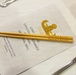 The image shows a formal place setting at a military ball event, featuring engraved wooden chopsticks resting on a printed program. The program and chopsticks both reference the 'Pacific EOD Ball 2026,' held on Saturday, August 22, 2026, at Camp Shields, Crow's Nest, Okinawa. The event is identified as a Joint Pacific Explosive Ordnance Disposal Memorial Ball.