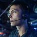 A U.S. Navy sailor wearing a Sennheiser communications headset is photographed in a dimly lit combat information center or operations room aboard a naval vessel. The sailor is wearing a dark blue Navy working uniform with a name tag reading 'FC3 PORTER' and a ship's crest badge visible on the chest. The blue-tinted lighting and background displays suggest an active operational environment.