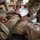 Preparing to Save Lives: CJTF - HOA Medics Conduct MASCAL Exercise Military personnel in OCP (Operational Camouflage Pattern) uniforms are conducting a medical training exercise. One soldier is lying on what appears to be a litter or stretcher while others practice securing the patient with straps. This appears to be a combat casualty care or tactical combat casualty care (TCCC) training scenario.