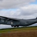 A U.S. Air Force C-130 Hercules military transport aircraft is captured in low-altitude flight, likely during takeoff or landing. The aircraft bears tail code 'RS' and serial number '85683', painted in overall gray livery. Motion blur on the ground and vegetation indicates the photo was taken with a panning technique to track the moving aircraft.