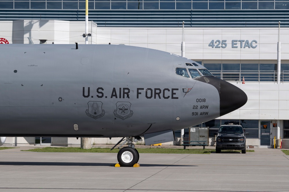 A U.S. Air Force aircraft, identified as serial number 0018 assigned to both 22 ARW and 931 ARW, is parked on a tarmac in front of a building marked '425 ETAC'. The aircraft displays two unit insignia patches on its fuselage and features the standard gray military paint scheme with a black radome nose. A black Ford pickup truck is visible in the background near the facility entrance.