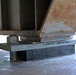 The image shows a close-up view of a bridge bearing assembly, specifically an elastomeric bearing pad supporting a steel girder on a concrete abutment or pier. The bearing pad is marked 'A1 559' and sits beneath a steel sole plate with a visible anchor bolt and nut. Surface rust and minor deterioration are visible on the steel girder components.