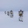 Green Berets, Danish SOF Ski Across Greenland Ice Cap During Operation Apex Indigo A column of military personnel in white winter camouflage uniforms are cross-country skiing across a flat, snow-covered terrain under an overcast sky. They are carrying rifles slung across their backs and using ski poles, moving in a single-file formation. The scene appears to be an arctic or subarctic military training exercise.