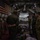 Green Berets, Danish SOF Ski Across Greenland Ice Cap During Operation Apex Indigo The image shows the interior of a military transport aircraft, likely a C-130 Hercules, with several personnel in military uniforms preparing equipment. An American flag is mounted on the left interior wall, and a banner reading 'LIVE FREE OR...' is visible on the right. Through the open rear cargo ramp, another C-130 aircraft is visible on the tarmac outside.