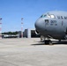 A U.S. Air Force C-17 Globemaster III military transport aircraft, tail number 0177, assigned to the 105th Airlift Wing, is parked on an airport tarmac. Ground crew personnel are visible performing pre/post-flight servicing activities around the aircraft. The scene appears to be at a military or joint-use airfield, with hangars and other aircraft visible in the background.