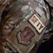 Close-up photograph of a U.S. military uniform sleeve displaying two patches on a MultiCam/OCP camouflage uniform. The patches identify the wearer as affiliated with U.S. Air Forces in Europe (USAFE) and carrying a 'SFTY' (Safety) functional designation. The image is a detail shot focused on the left shoulder area of the uniform.