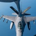 An aerial refueling operation is underway, with a KC-135 or similar tanker aircraft extending its boom toward an F-16 Fighting Falcon fighter jet. The photo is taken from the tanker's boom operator window looking down at the receiver aircraft. The F-16 is armed with multiple air-to-air missiles and carries external fuel tanks, and bears markings indicating it belongs to an Air National Guard (ANG) unit.