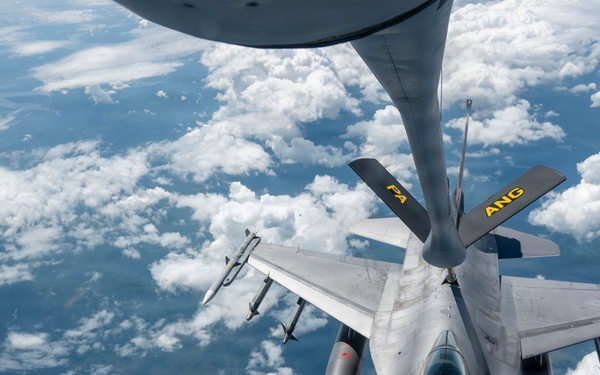 An aerial refueling operation is taking place between a tanker aircraft (visible at top) and an F-16 Fighting Falcon fighter jet. The F-16, marked with 'ANG' (Air National Guard) and 'FA' tail codes, is receiving fuel via a boom refueling system at high altitude. The image is taken from the tanker aircraft's boom operator window, looking down at the receiver aircraft with cloud cover and terrain visible far below.