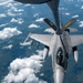 An F-16 Fighting Falcon fighter jet is conducting an aerial refueling operation with a tanker aircraft, visible at the top of the frame. The fighter jet bears markings 'PA' and 'ANG' on its tail fins, indicating it belongs to the Pennsylvania Air National Guard. The aircraft is flying at altitude above scattered cloud cover over what appears to be a rural landscape.