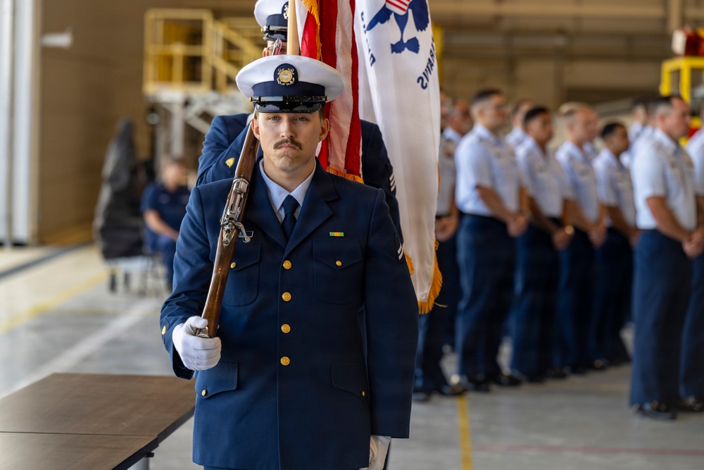 U.S. Coast Guard Color Guard member presents colors during ceremonial event inside hangar