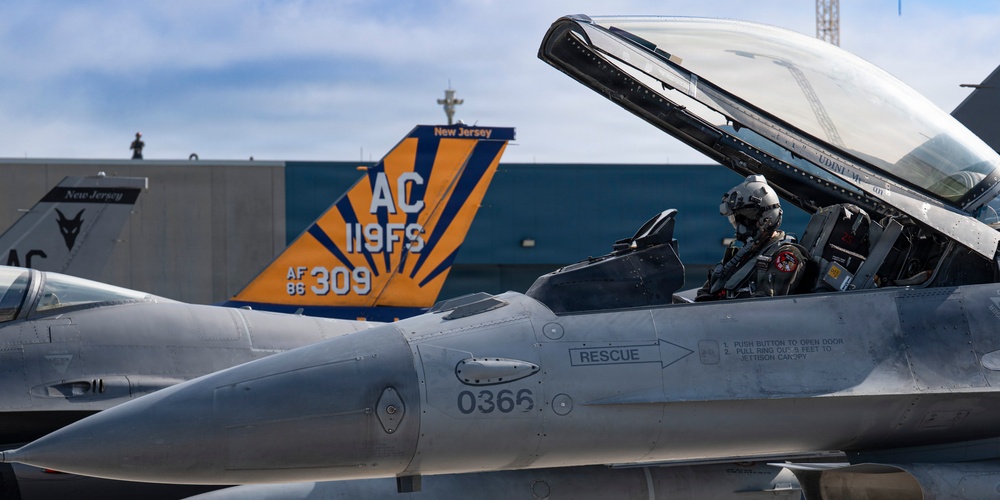 The image shows multiple F-16 Fighting Falcon jet fighters on a flight line, belonging to the New Jersey Air National Guard's 119th Fighter Squadron. A pilot in full flight gear is seated in the cockpit of the foreground aircraft (serial 0366), with the canopy open. A distinctive blue and orange tail marking with 'AC 119FS' and 'AF 86 309' is prominently visible in the background.