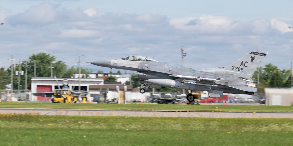 An F-16 Fighting Falcon jet fighter is captured during takeoff or landing on a runway. The aircraft bears tail markings 'AC 366' and 'AF 86' with a 'New Jersey' designation, identifying it as belonging to the New Jersey Air National Guard. Ground support equipment and airport infrastructure are visible in the background.