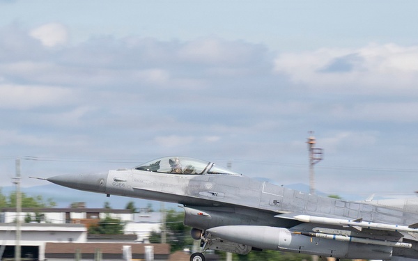An F-16 Fighting Falcon jet fighter is captured during takeoff or landing on a runway. The aircraft bears tail markings 'AC 366' and 'AF 86' with a 'New Jersey' designation, identifying it as belonging to the New Jersey Air National Guard. Ground support equipment and airport infrastructure are visible in the background.