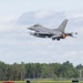 An F-16 Fighting Falcon jet fighter is captured just after takeoff from a military airfield, with its afterburner visibly glowing orange. The aircraft bears tail code 'AC' and serial number '345', consistent with the New Jersey Air National Guard's 177th Fighter Wing. A runway designation sign reading '36-18' is visible in the foreground, with a tree line in the background.