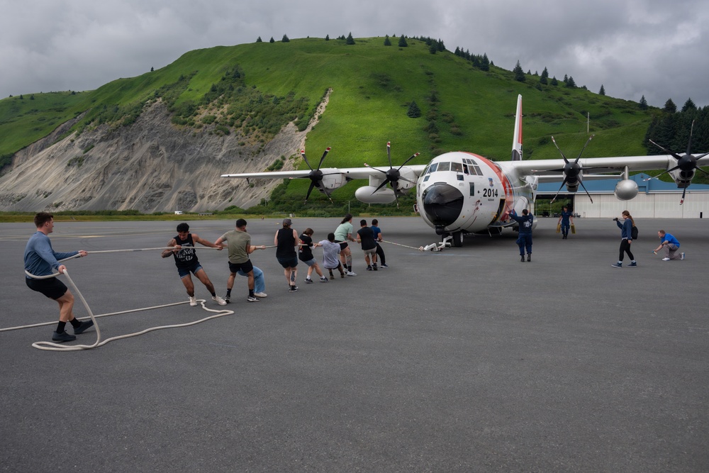Coast Guard personnel compete to pull an HC-130J Super Hercules airplane in Kodiak, Alaska
