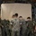 Air Force, Marines conduct joint training on C-17 A group of military personnel in digital camouflage uniforms are working together inside what appears to be a military cargo aircraft. They are collectively pushing or maneuvering a large tan/beige covered object, likely a piece of equipment or cargo. The scene depicts a coordinated loading or unloading operation within the aircraft's cargo bay.