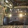Air Force, Marines conduct joint training on C-17 A military HMMWV (Humvee) is being loaded or unloaded from the cargo bay of a large military transport aircraft, likely a C-17 Globemaster or C-130. Two personnel are visible inside the Humvee with headlights illuminated, while a third soldier in MultiCam/OCP uniform stands to the left guiding the operation. The interior of the aircraft cargo hold is clearly visible with its characteristic ribbed flooring and wall-mounted equipment.