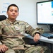 A U.S. Space Force member with the name tag 'Luna' and rank insignia of a 2nd Lieutenant is seated at a workstation with dual Dell monitors. The individual is wearing OCP (Operational Camouflage Pattern) uniform with a U.S. Space Force chest tape and a XVI unit patch on the left sleeve. The setting appears to be an office or operations center environment.