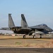 An F-15 Eagle fighter jet is taxiing on a runway at what appears to be a California Air National Guard base. The aircraft bears tail number 165 with 'AF 86' and 'CALIFORNIA' markings, and features a distinctive bird/eagle emblem on the vertical stabilizer. The location appears to be Fresno Air National Guard Base based on visible markings.