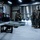 Military personnel in camouflage uniforms are gathered inside a hangar facility with unmanned aerial vehicles (UAVs/drones). A fixed-wing drone on a ground support stand is prominently visible in the foreground, while service members appear to be conducting training or maintenance operations. The setting appears to be a military UAV operations or maintenance facility.