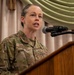 A U.S. Air Force service member named Sargent, wearing OCP (Operational Camouflage Pattern) uniform, is speaking at a podium with a microphone. The name tape reads 'SARGENT' and the branch tape reads 'US AIR FORCE,' with a Master Sergeant rank insignia visible on the chest. The setting appears to be a formal indoor military event or ceremony.
