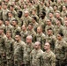 A large formation of U.S. Army soldiers standing at attention in what appears to be an indoor military ceremony or formation event. All personnel are wearing the Army Combat Uniform (ACU) in Operational Camouflage Pattern (OCP). The formation consists of both male and female soldiers arranged in multiple rows extending deep into the background.