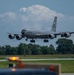 A U.S. Air Force KC-135 Stratotanker aerial refueling aircraft is captured on final approach to land at an airfield. The aircraft is in standard gray livery with 'U.S. AIR FORCE' markings clearly visible on the fuselage. Landing gear is fully deployed, indicating imminent touchdown.