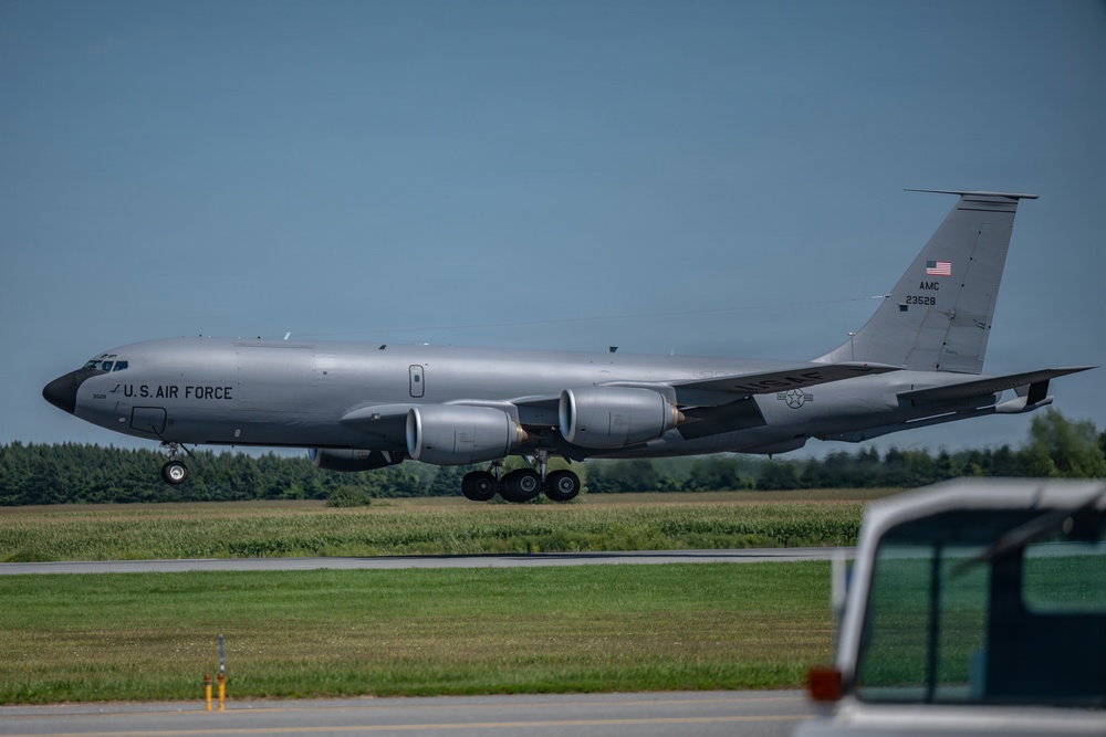 A U.S. Air Force KC-135 Stratotanker aerial refueling aircraft is taxiing or taking off on a runway. The aircraft bears the tail number 23528 and AMC (Air Mobility Command) markings, along with a U.S. flag on the tail. The setting appears to be a military or joint-use airfield surrounded by green vegetation under clear skies.