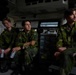 Three young soldiers in Swedish military camouflage uniforms are seated inside what appears to be a military vehicle or command post interior. They are wearing identical M90 pattern camouflage uniforms with visible Swedish flag patches on their shoulders. The setting appears to be the interior of an armored personnel carrier or similar military vehicle.