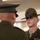 Alpha Company Battalion Commander’s Inspection Two U.S. Marine Corps personnel are shown in a formal indoor setting, facing each other. The Marine in focus is wearing a Drill Instructor campaign cover (campaign hat) with the Eagle, Globe, and Anchor emblem, along with service ribbons on his dress uniform. The scene appears to depict a formal inspection or ceremony.
