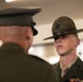 Two U.S. Marine Corps personnel are shown in a formal indoor setting, facing each other. The Marine in focus is wearing a Drill Instructor campaign cover (campaign hat) with the Eagle, Globe, and Anchor emblem, along with service ribbons on his dress uniform. The scene appears to depict a formal inspection or ceremony.