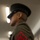 Alpha Company Battalion Commander’s Inspection A close-up photograph focusing on the sleeve insignia of a United States Marine Corps dress uniform. The patch is a red chevron with crossed rifles, indicating the rank of Lance Corporal (E-3). The subject's face is intentionally blurred in the background, with the rank patch as the sharp focal point.