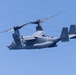A United States Air Force CV-22 Osprey tiltrotor aircraft is captured in flight against a clear blue sky. The aircraft is painted in a dark gray/charcoal color scheme consistent with special operations use. Tail markings indicate it belongs to the USAF with the identifier '0065' visible on the tail fin.
