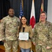 A civilian woman named Veronica Lewis is being recognized with a Department of the Army Civilian Service Commendation Medal certificate. She is flanked by two U.S. Army soldiers — one identified by nametape as 'Davis' on the left and 'Johnson' on the right — in a formal award ceremony setting. The event appears to take place in Japan, as indicated by the Japanese flag visible in the background.