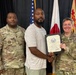 Three individuals pose for a formal recognition photo, with a civilian man in the center holding a certificate alongside a U.S. Army female soldier on the right and a male U.S. Army soldier named Davis on the left. The certificate appears to be awarded to Maurice V. Fowler Jr. in recognition of twenty years of service to the United States Government. The setting appears to be an official military ceremony room with American and other flags visible in the background.