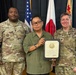 Three individuals pose for a formal photo at what appears to be a U.S. Army recognition ceremony. The civilian in the center, identified on the certificate as Richard T. Ahana, is holding a plaque recognizing thirty-five years of service to the United States Government. Two U.S. Army soldiers in OCP camouflage uniforms flank him, with name tapes reading 'Davis' on the left and 'Johnson' on the right.