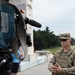 A U.S. Army soldier, identified by name tape as 'Blanchard,' is being interviewed on camera near the National Mall in Washington, D.C. The Washington Monument is clearly visible in the background, along with the reflecting pool area. The soldier is in full camouflage uniform with a general officer star visible on his cap.
