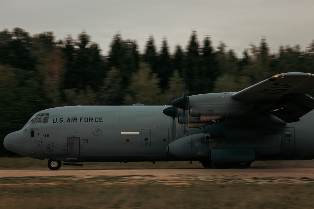 A U.S. Air Force C-130 Hercules military transport aircraft is taxiing or rolling on a runway or unpaved airstrip. The aircraft bears the markings 'U.S. AIR FORCE' and the tail number '4631' on its fuselage. The image was taken with a panning technique, resulting in motion blur in the background while the aircraft remains relatively sharp.