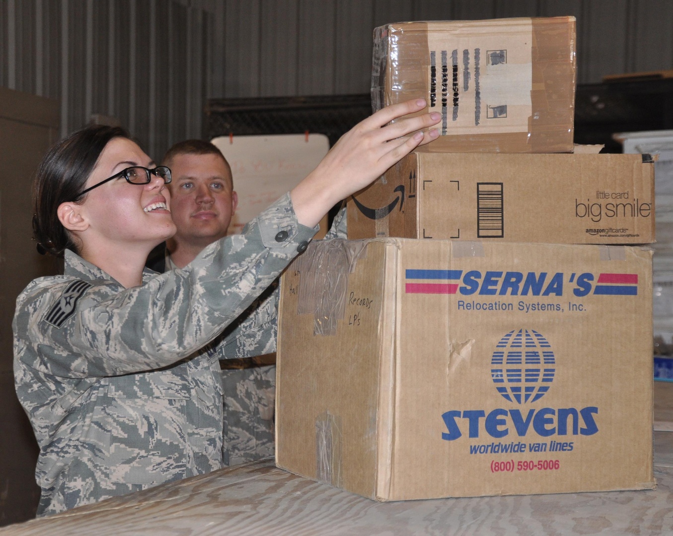 Staff Sgt. Robert W. Monohan, American Forces Network Theater Maintenance Technician, looks on as Staff Sgt. Jessica L. King, AFN Bagram News NCOIC, picks up holiday packages for her unit at the Bagram Airfield post office.
