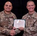 Two U.S. Army soldiers pose together holding a Meritorious Service Medal certificate. The soldier on the left, identified by name tape as 'TELLEZ,' is receiving the award and is wearing the medal on his uniform. The soldier on the right, identified as 'HULL,' appears to be the presenting officer, and both are shaking hands for the ceremonial photo.