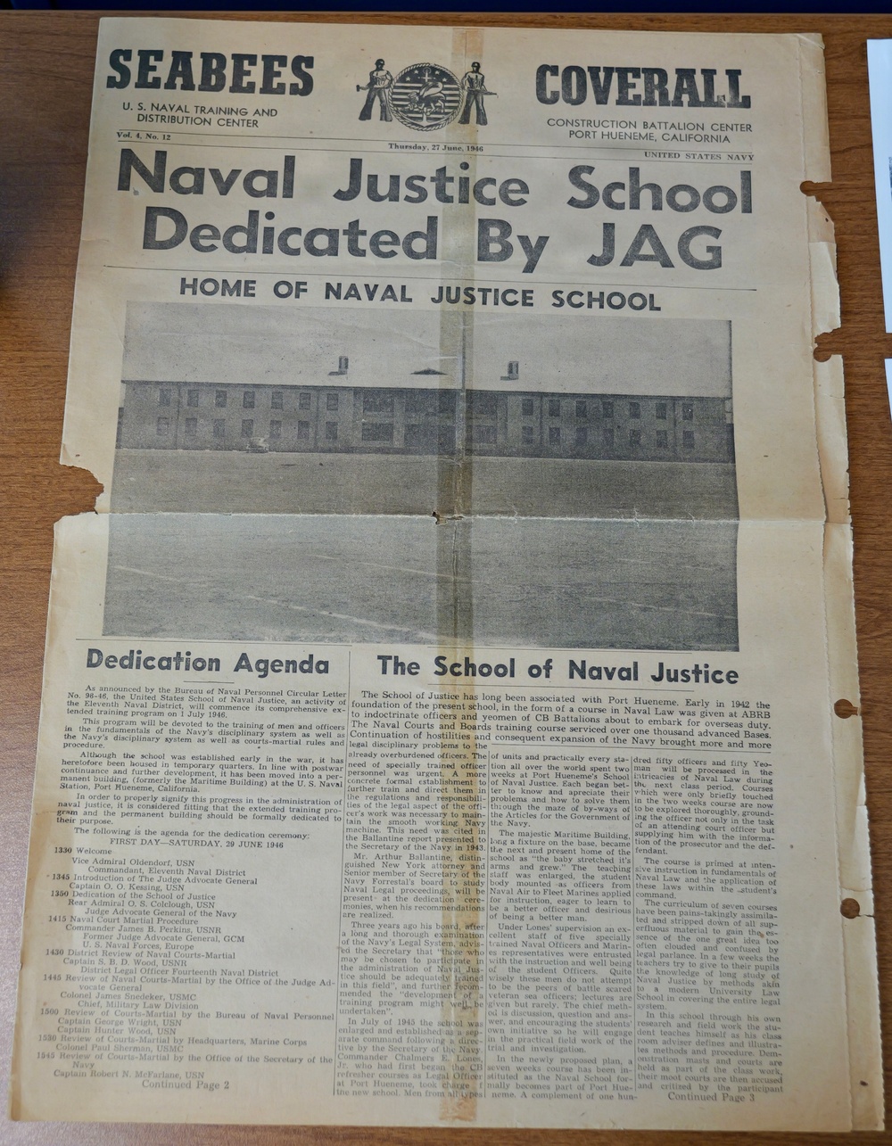 This is a photograph of a historical U.S. Navy newspaper called 'Seabees Coverall' dated Thursday, 27 June 1946, published at the Construction Battalion Center, Port Hueneme, California. The front page features the headline 'Naval Justice School Dedicated By JAG' along with a photograph of the school building and two articles: 'Dedication Agenda' and 'The School of Naval Justice'. The newspaper documents the formal dedication of the United States Naval Justice School as part of the Navy's post-WWII institutional development.