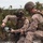 BLT 1/8 conducts organic munitions range Two military personnel in desert camouflage uniforms are crouched in an outdoor field environment, examining what appears to be a drone controller or remote control device. Both individuals are wearing tactical gear including helmets, body armor, and equipment vests. The setting appears to be a training exercise or field operation in a scrubland environment.