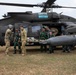 Military medical personnel from what appear to be U.S. and Indonesian armed forces are conducting a MEDEVAC exercise beside a black UH-60 Black Hawk helicopter marked 'Arctic Dustoff'. Personnel are carrying a simulated casualty on a stretcher toward the helicopter. The helicopter bears a red cross medical insignia on its external fuel tank, indicating its medical evacuation role.