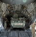 A U.S. Army Stryker armored fighting vehicle is being loaded into the cargo bay of a large military transport aircraft, likely a C-17 Globemaster III. The vehicle bears the markings 'A31', '1-28 IN / 4ID', and 'SPEARHEADER', identifying it as belonging to the 1st Battalion, 28th Infantry Regiment, 4th Infantry Division. Several soldiers in camouflage uniforms are guiding and supervising the loading operation on the aircraft's rear ramp.