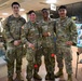 Four U.S. Army soldiers in OCP (Operational Camouflage Pattern) uniforms pose together smiling inside what appears to be a Japanese facility or store, indicated by Japanese signage in the background. Two of the soldiers are holding kendama (traditional Japanese cup-and-ball toys), suggesting a cultural exchange or leisure activity. Name tapes visible on the uniforms read HART, RENFRO, BREGGINS, and RICE.