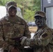 Two U.S. Army soldiers in OCP (Operational Camouflage Pattern) uniforms are posing together while shaking hands and exchanging what appears to be a certificate or document. The soldier on the left, identified by his name tape as 'Collins,' wears a Command Sergeant Major rank insignia on his cap, suggesting this is an award or recognition ceremony. The soldier on the right has tactical face paint applied, indicating recent or ongoing field training exercises.