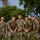 12th Combat Aviation Brigade hosts Danish Flyver March Five U.S. Army soldiers in OCP (Operational Camouflage Pattern) uniforms pose together for a group photo outdoors. The center soldier's name tape reads 'GRANT' and a 'U.S. ARMY' tape is visible. They appear to be at a military installation or training area, with a Yagi-style antenna array visible in the background.