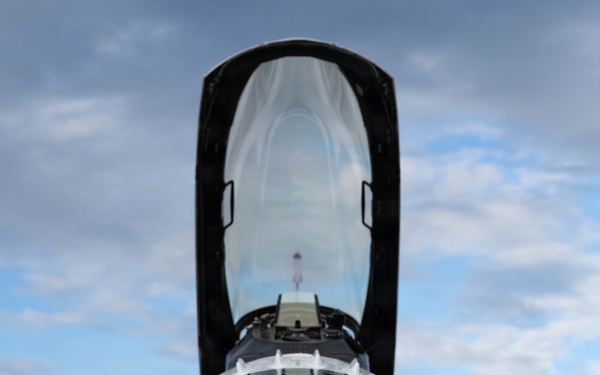 A front-facing close-up photograph of a U.S. Air Force Thunderbirds F-16 Fighting Falcon parked on a tarmac apron. The aircraft's canopy is open and raised, revealing the empty cockpit interior. The distinctive red and white Thunderbirds livery is prominently visible on the nose cone and fuselage.